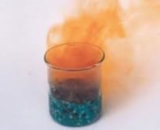 A fumaça vermelha é o gás dióxido de nitrogênio e o sólido preto é o óxido cúprico, formados na queima ou pirólise do nitrato de cobre. 